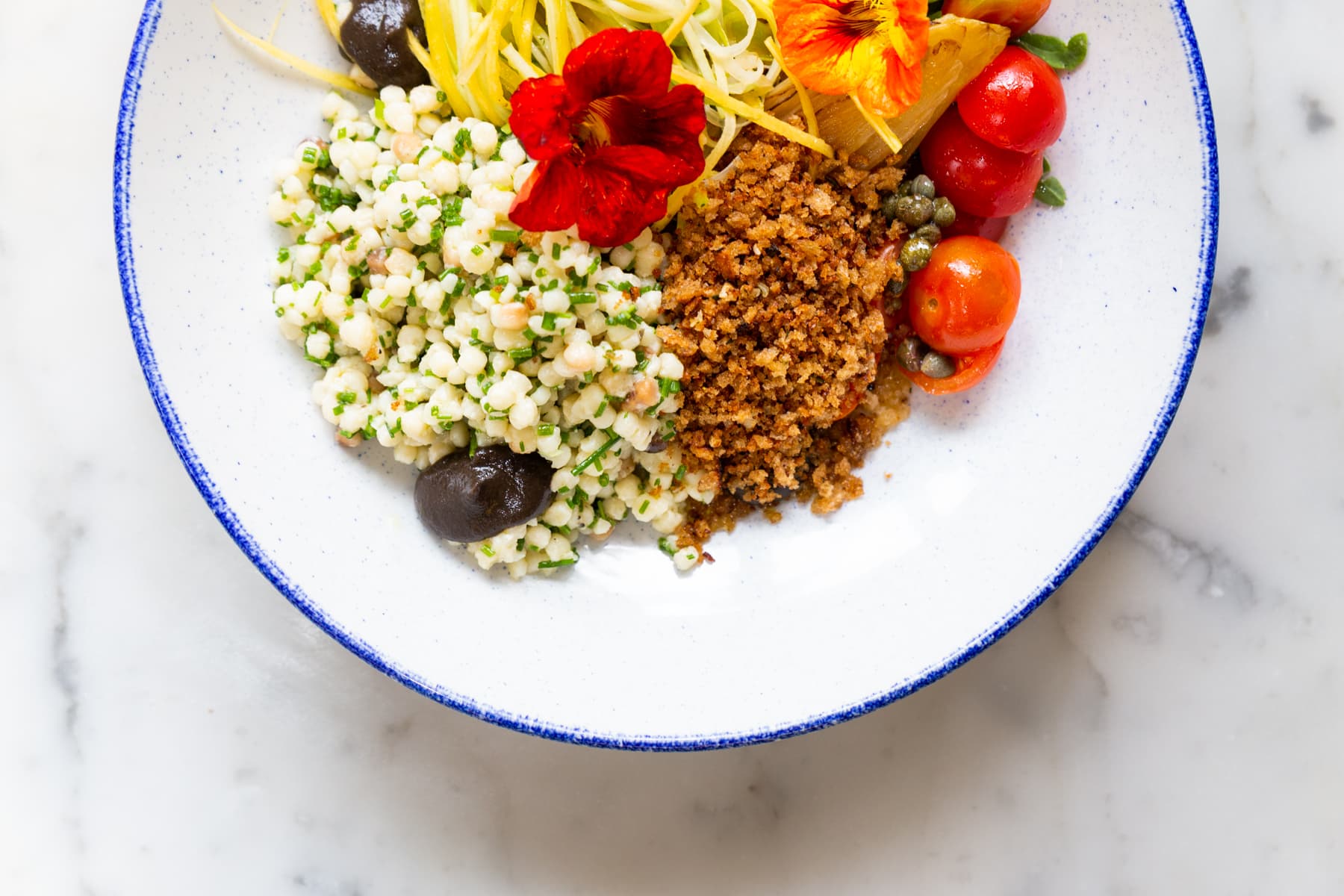 Fregola pasta met witlof, tomaat, courgette, zwarte olijven-crème en pangrattato
